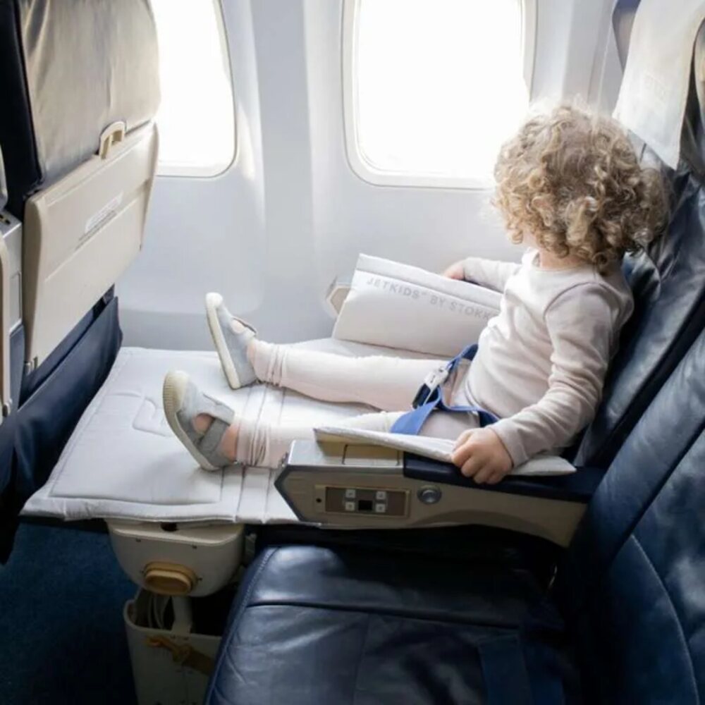 Child in plane seat with legs stretched out on Stokke Jet Kids Bed Box