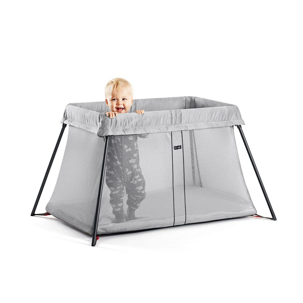 Baby Bjorn Travel Cot in grey with toddler standing up 